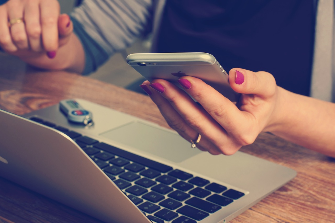 Very close up image of someone sat at a desk using a mobile phone to sign up to the newsletter