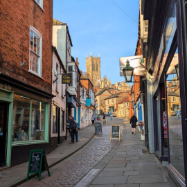 A view of The Straight, with the Cathedral spires in the background at the top of the hill against a blue sky.