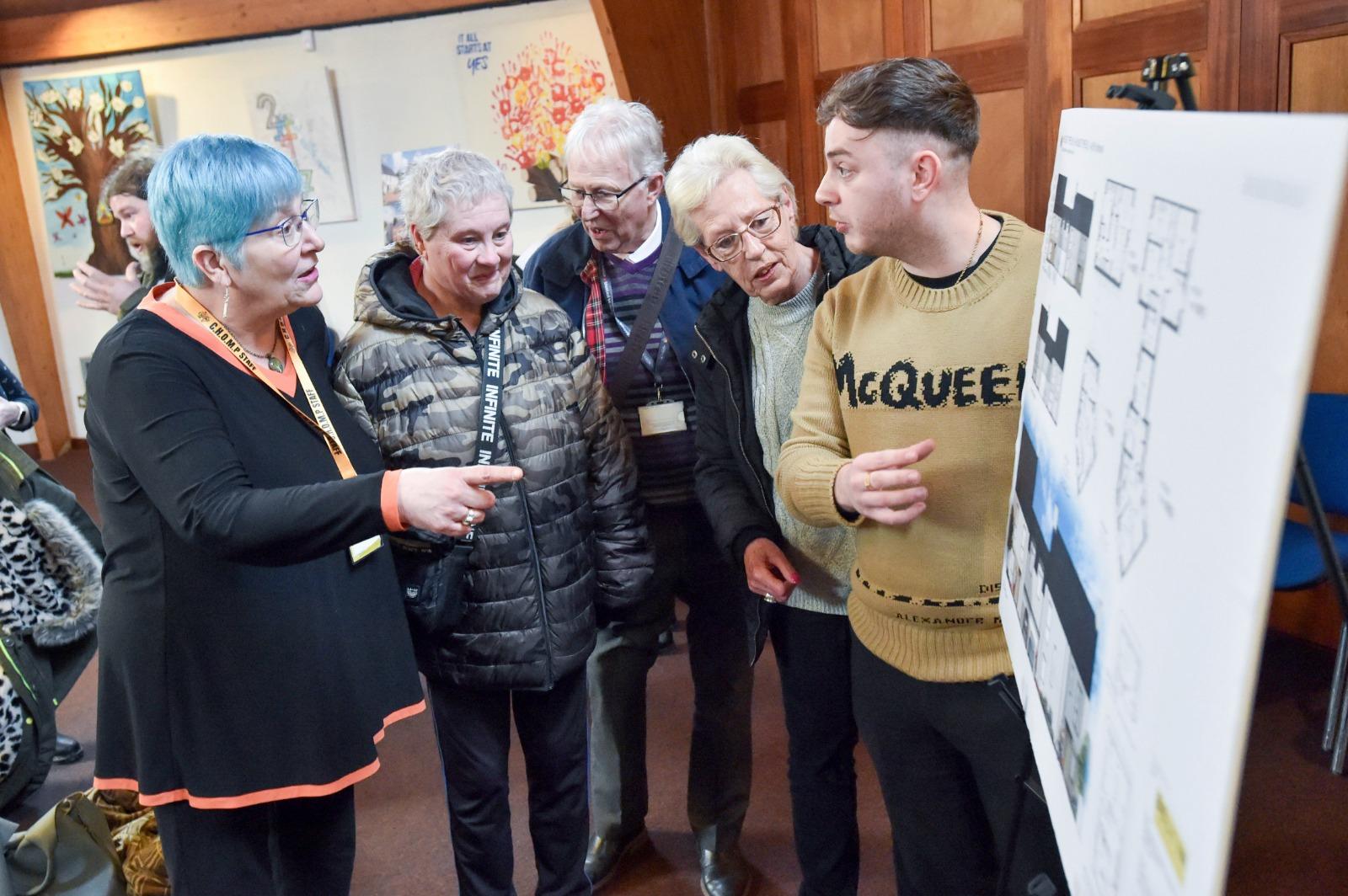 Four elderly members of the community, two women and two men, with a male member of council staff looking at a design board.