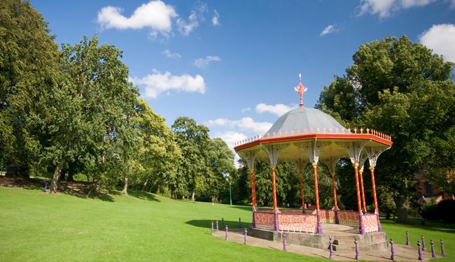 four people holding green flag outside in Arboretum park