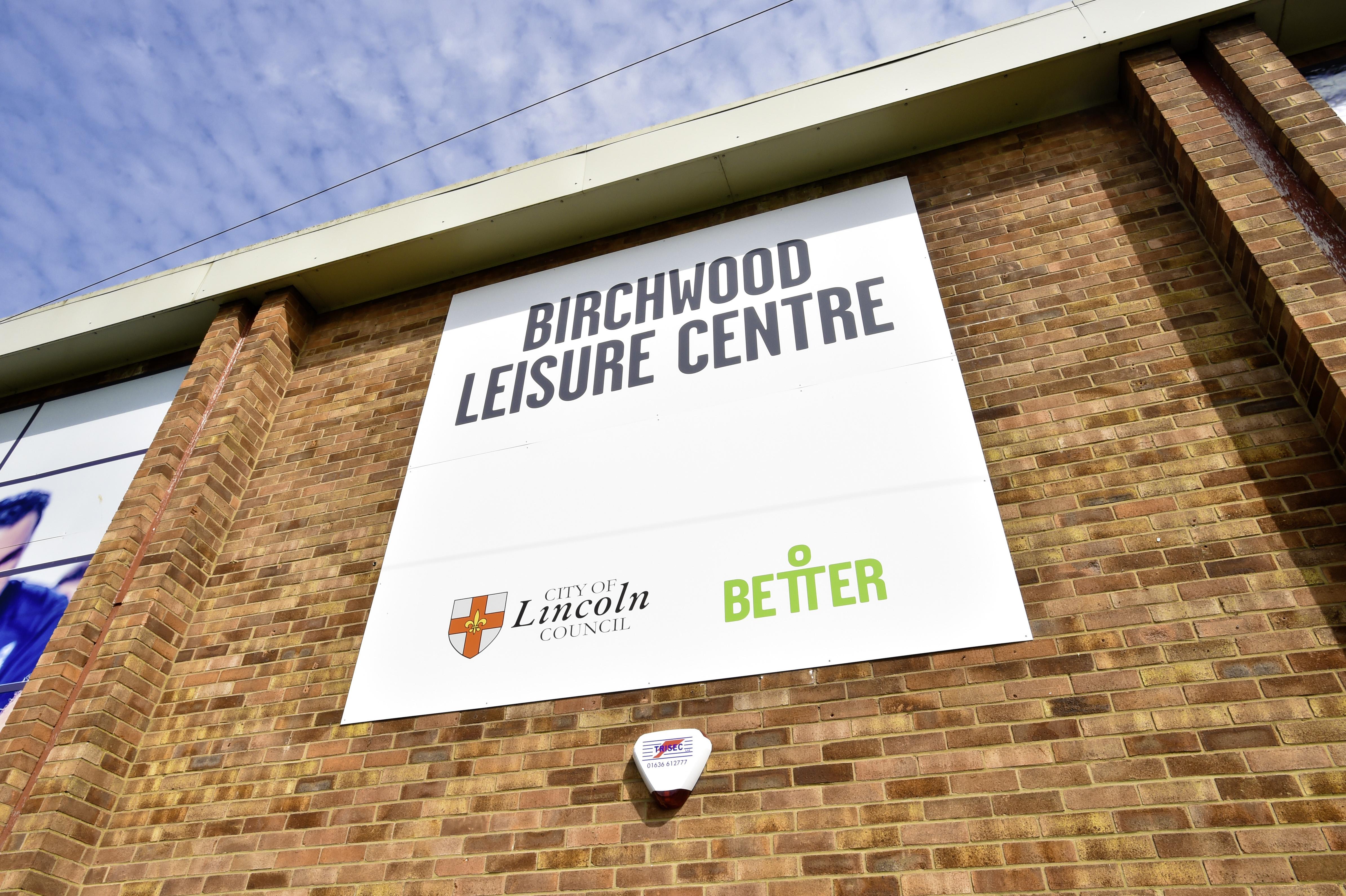 A white sign on a brick wall on Birchwood Leisure Centre.