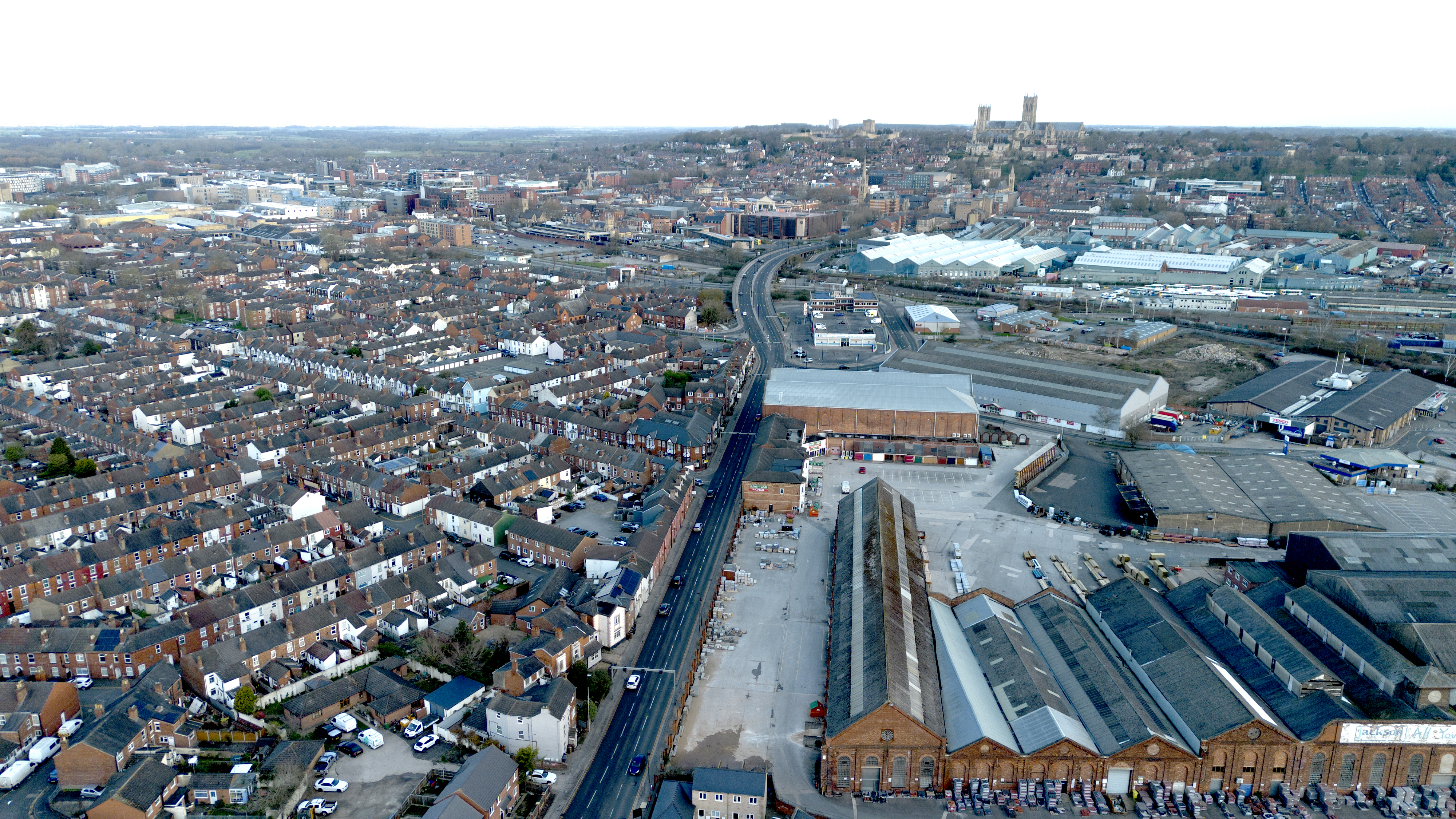 A drone picture of Lincoln's city centre, may terraced houses can be seen with a few industrial buildings and factories as well as Lincoln Cathedral in the distance.