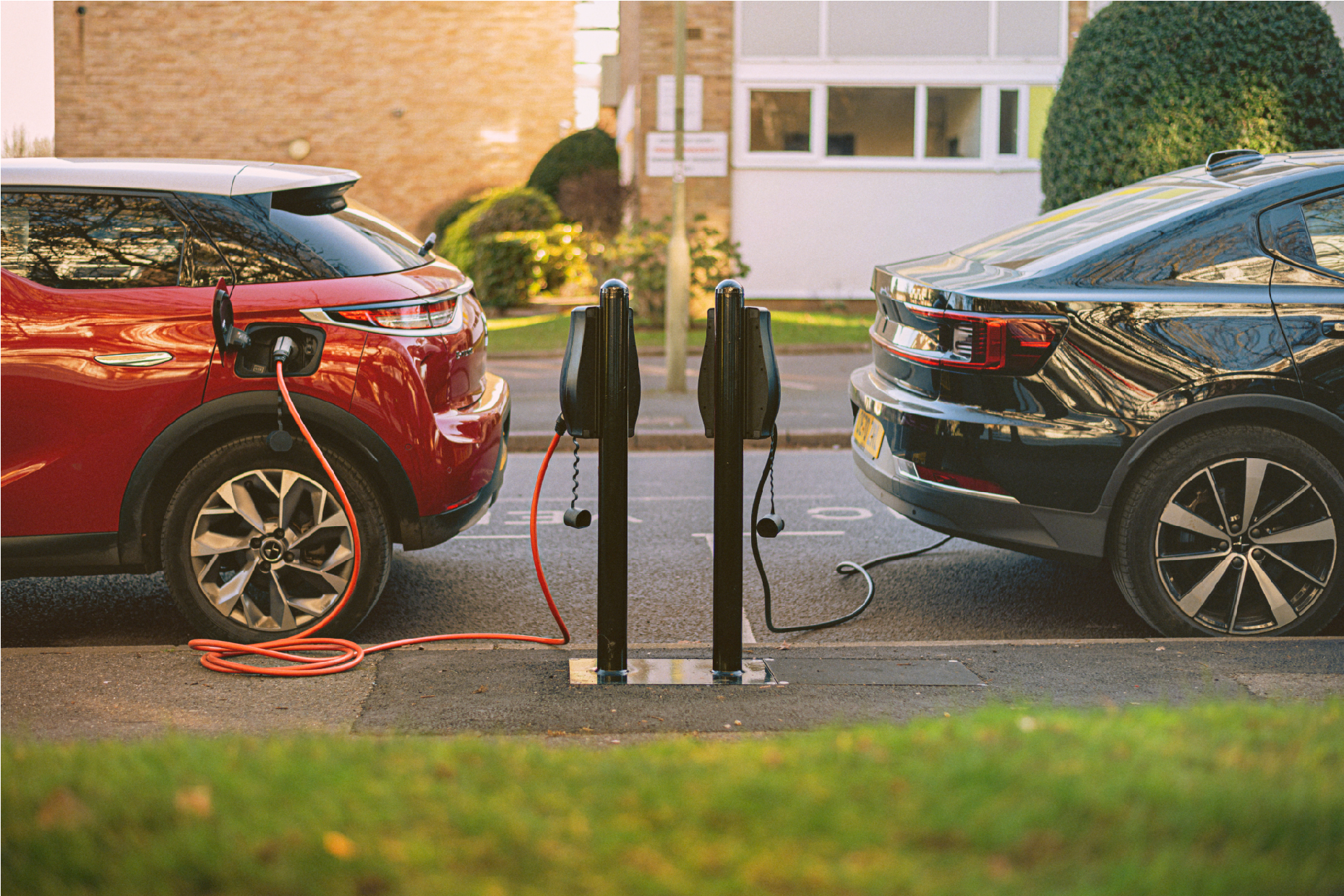 Image shows two cars, bumper to bumper charged into electric vehicle charging points