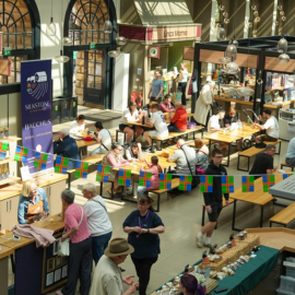 The inside of Cornhill Market taken from above on the mezzanine. A host of different traders and visitors occupy the building.