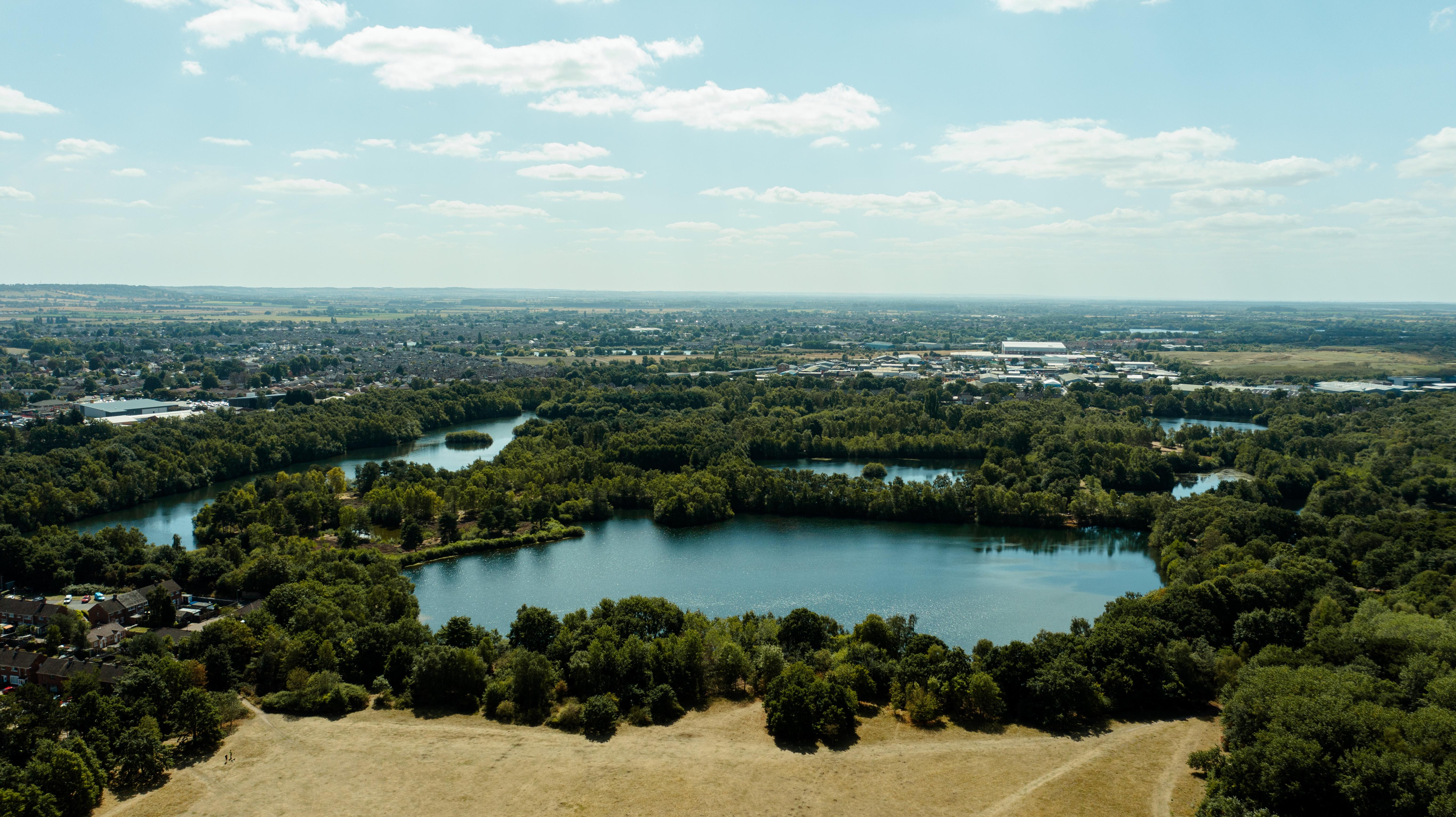 A done shot looking down on the lake, field and trees in Hartsholme Country Park.