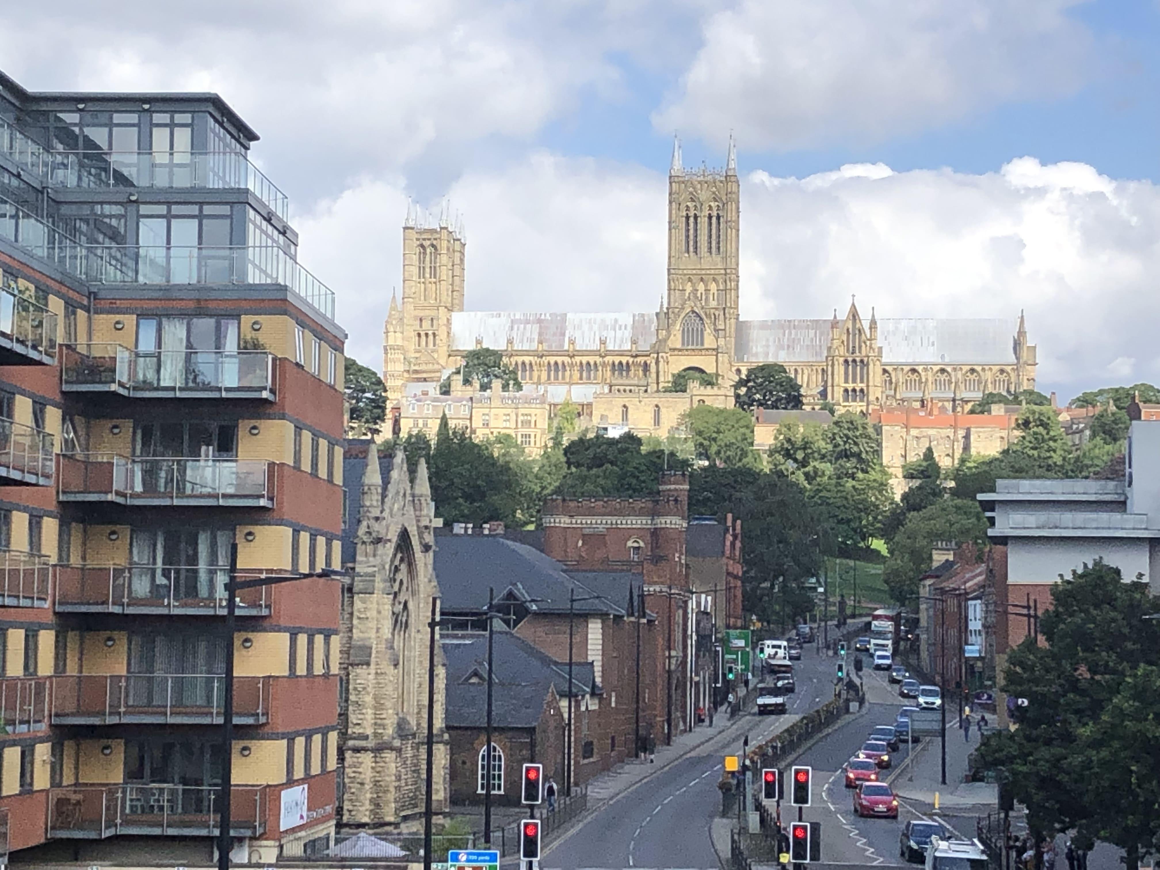 The road below Lincoln Cathedral and lots of tall buildings in the foreground