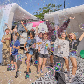 A group of young people celebrate in front of the Zone Go space, surrounded by bubbles.