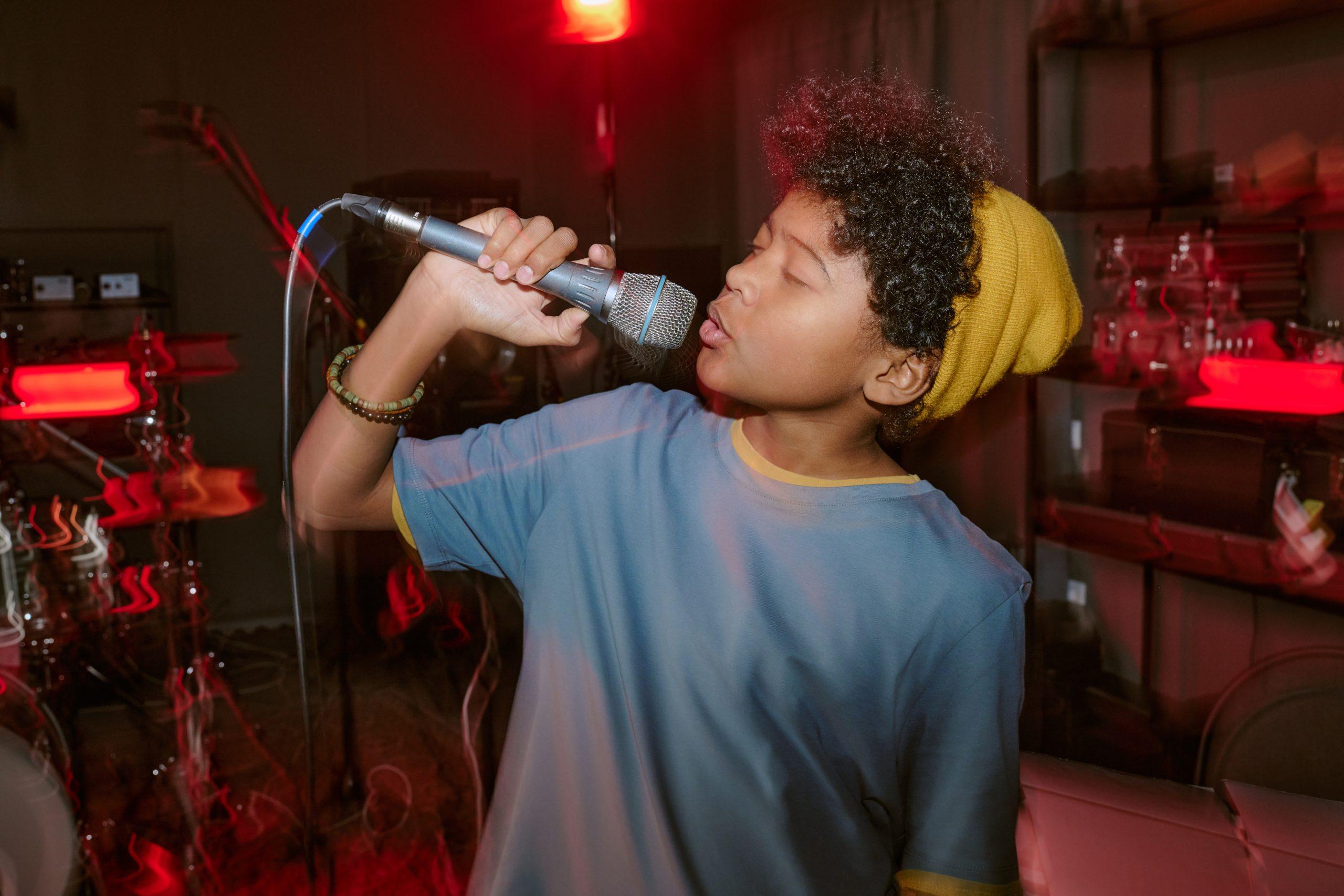 A student at Noise Academy showcasing their singing skills, raising a microphone up to their mouth.