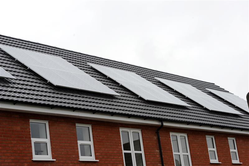 Houses shown from the first floor window up with grey roofs with large square solar panels attached.