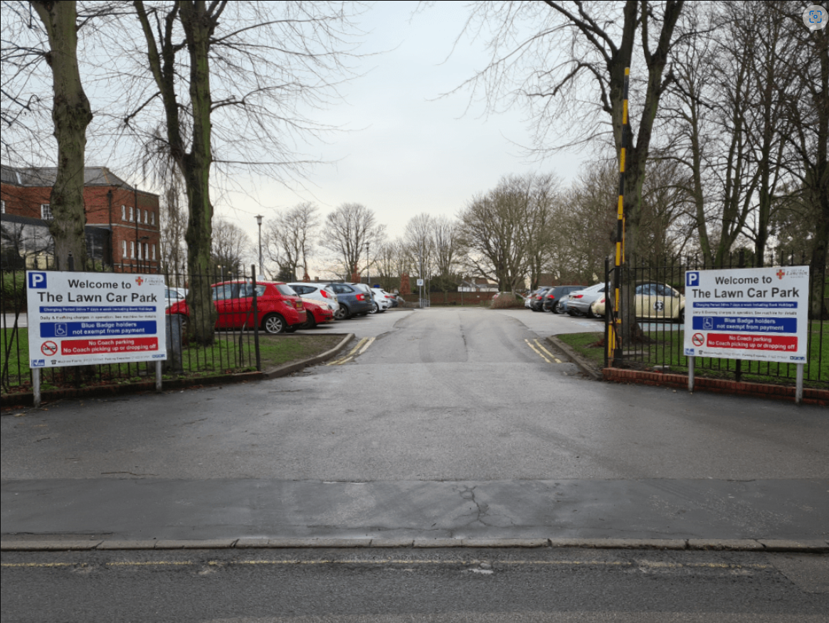 Entrance to the car par park showing lots of parked cars.