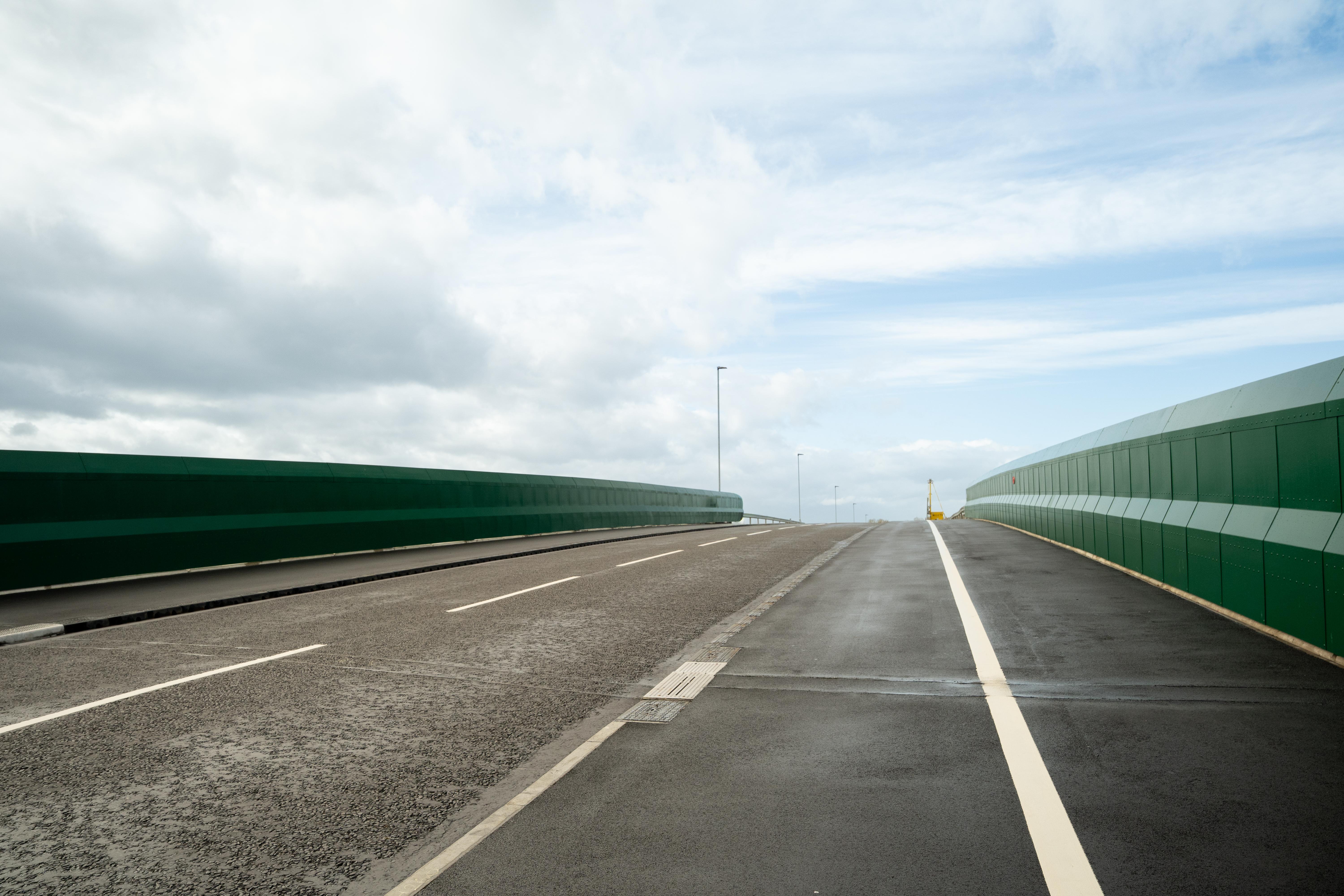 A picture of a road bridge with green barrier walls either side of the road.