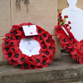 A wreath of poppies lie against the War Memorial.